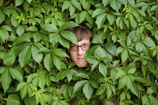 man hiding in bushes, peeking out