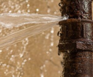 water spraying from a burst rusty pipe